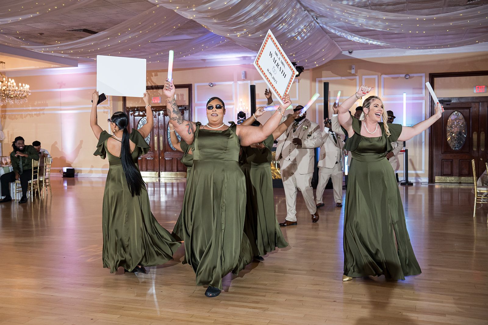 Beautiful bridesmaids wearing green bridesmaid dresses and dance at the elegant wedding venue near Philadelphia