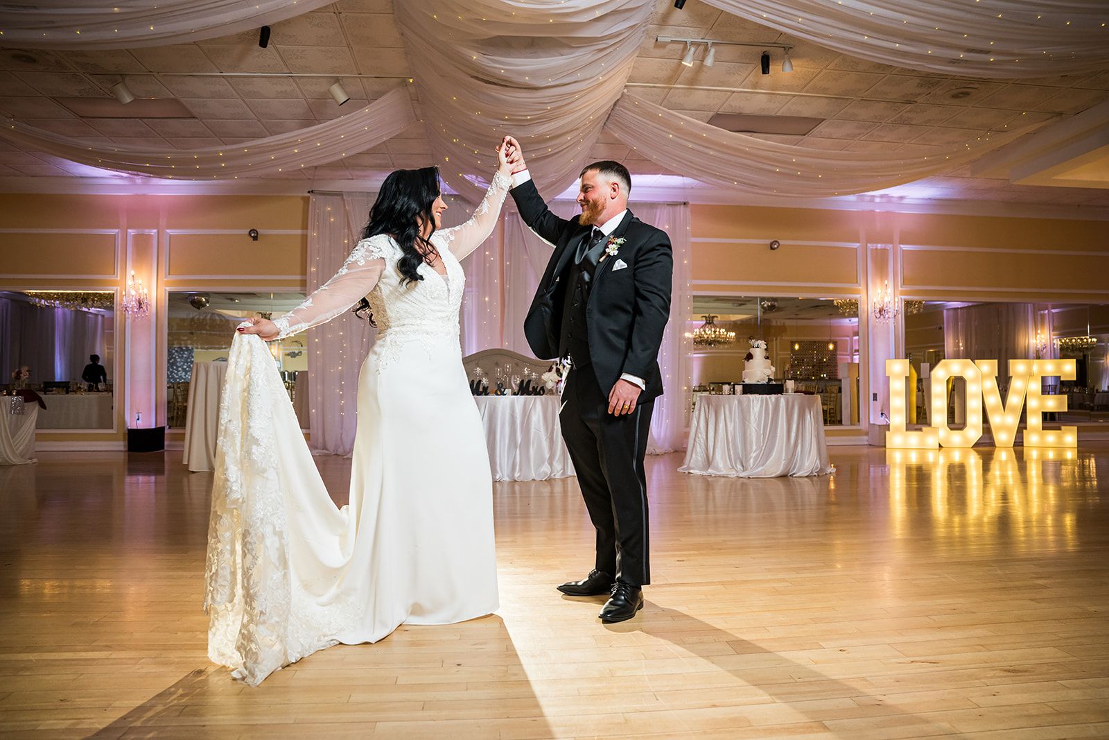 Bride & groom wearing designer wedding dress and formal suit enjoy their first dance at an elegant ballroom wedding venue for 250 wedding guests at an all inclusive wedding venue near New Jersey